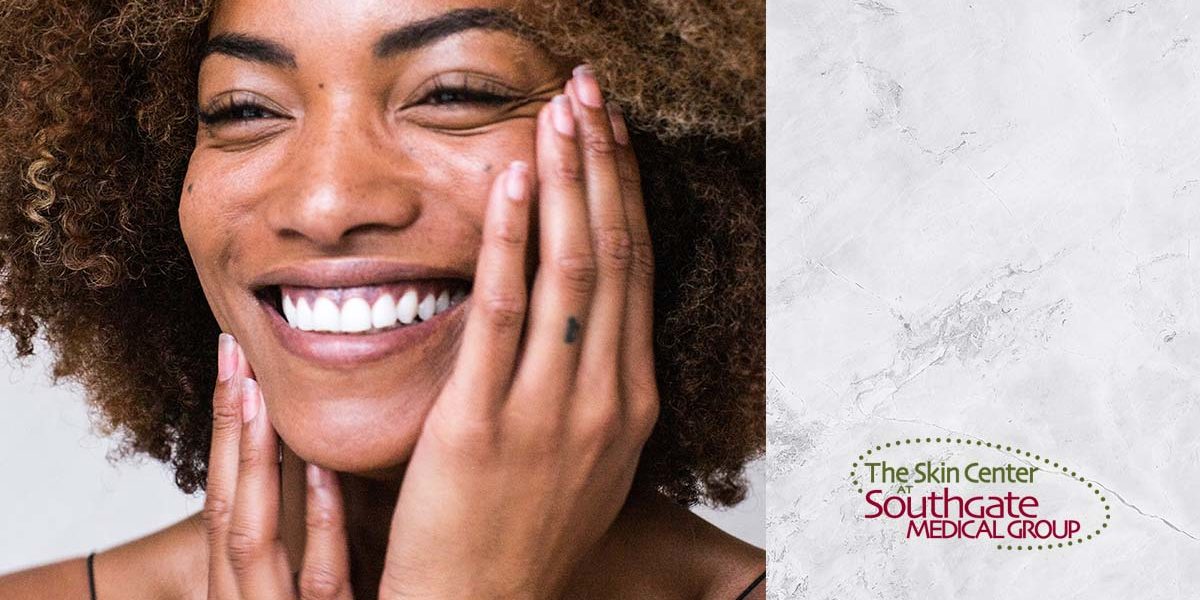 4-WAYS-TO-PREPARE-YOUR-SKIN-FOR-WINTER-WEATHER A lovely young woman with dark sin and a bright smile touches her face as if experiencing the soft and silky skin beneath her fingertips. A Southgate Skin center logo sits in the bottom-right corner.