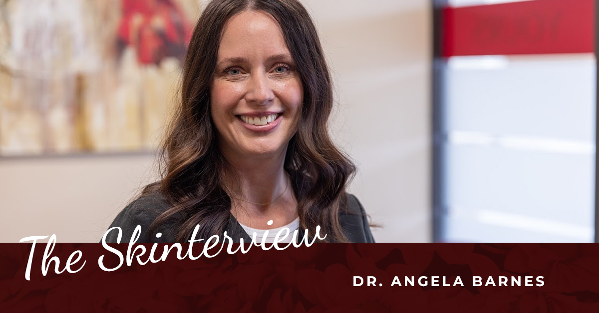 Angela Barnes_Skin Center The Skinterview: Dr. Angela Barnes. A brunette woman, a medical professional, smiles in the lobby of The Skin Center
